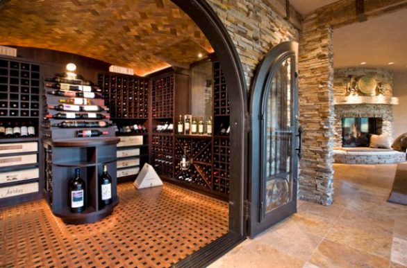 Large-archway-with-iron-doors-and-wooden-flooring-give-this-wine-storage-space-a-traditional-look
